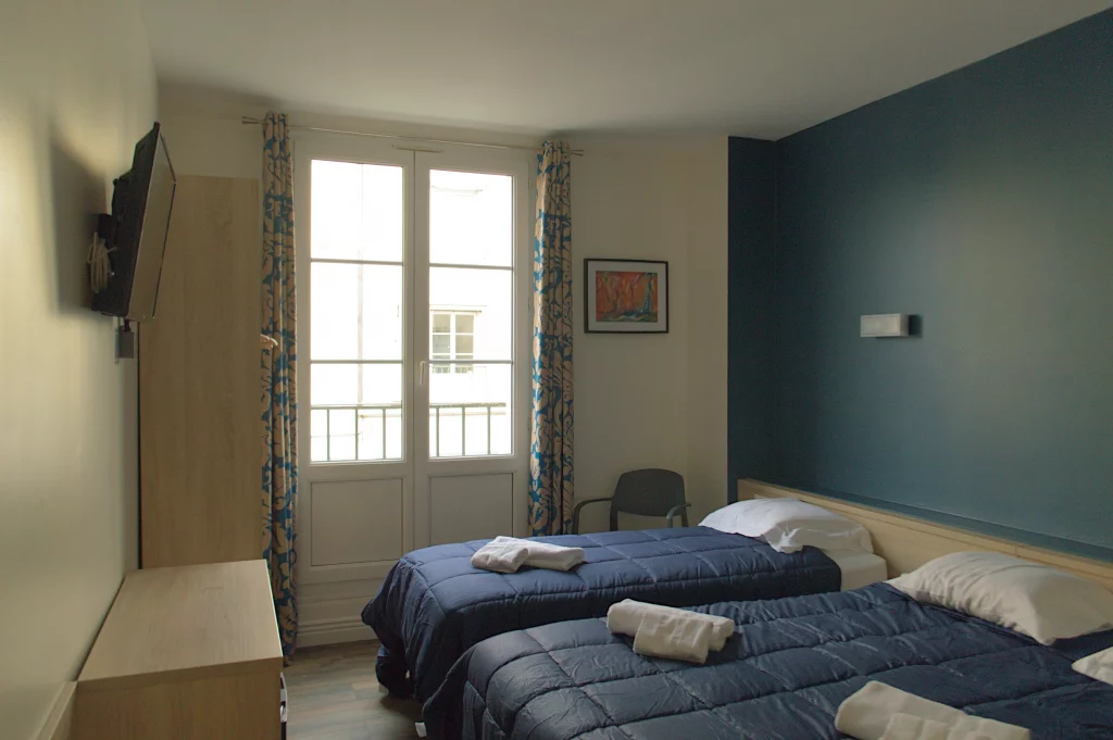 Photo d'une chambre triple, il y à un lit double et un lit simple, les deux lits ont une couverture bleu